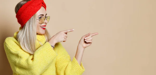 Mujer joven señala los dedos para la expresión del espacio de texto emoción en gafas de sol de moda suéter amarillo y labios rojos — Foto de Stock