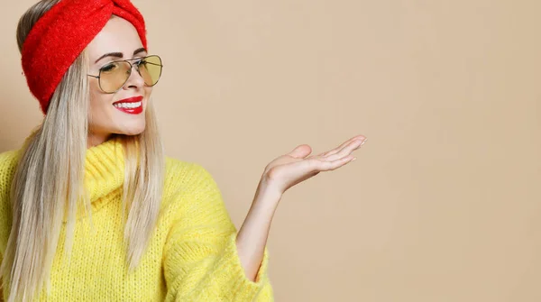 Jovem mulher apontar palma da mão aberta para expressão de espaço de texto emoção na moda óculos de sol suéter amarelo e lábios vermelhos — Fotografia de Stock