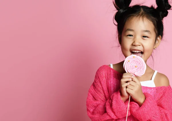 Счастливая маленькая азиатская девочка лизни съесть счастливый большой сладкий леденец конфеты на розовый — стоковое фото