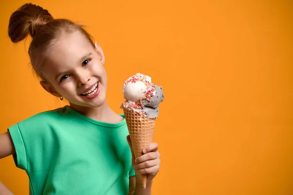 Küçük bebek kız çocuk waffle koni sarı arka plan üzerinde vanilyalı dondurma yeme. Afiş — Stok fotoğraf