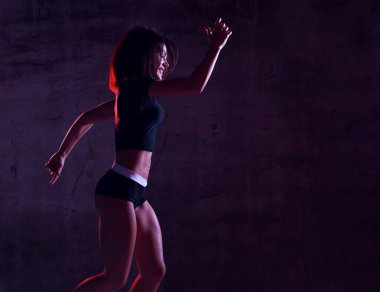 Gyn mavi ve pembe neon ışık karanlık duvara koşu çalışan genç spor kadın 