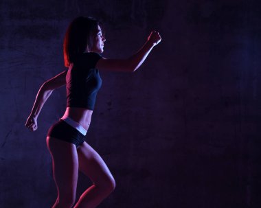 Gyn mavi ve pembe neon ışık karanlık duvara koşu çalışan genç spor kadın 