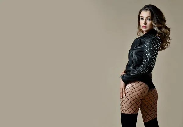 Mulher sexy bonita com nádegas de bunda agradável em jaqueta de couro moderno e óculos de sol de moda — Fotografia de Stock