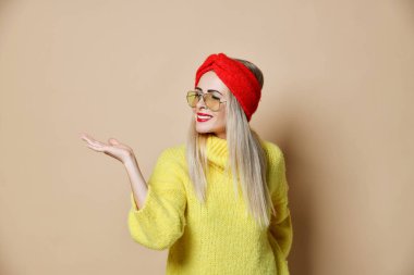 Genç kadın noktası açık el palm için metin alanı ifade duygu moda güneş gözlüğü sarı kazak ve kırmızı dudaklar 