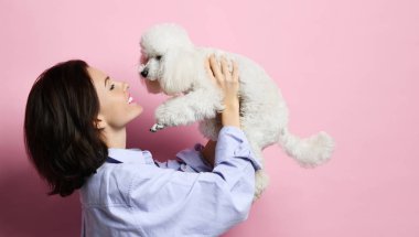 Güzel kadın üzerinde pembe mutlu gülümseyen güzel beyaz kaniş köpek köpek sarılma