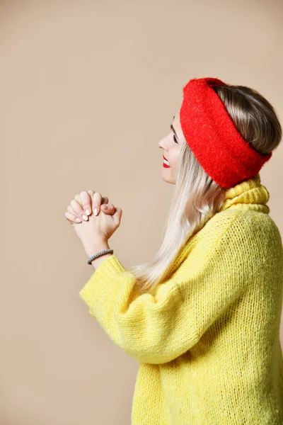 Mulher bonita orando, mãos apertadas juntas em suéter amarelo — Fotografia de Stock