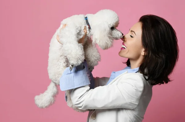 Mooie vrouw haar mooie witte poedel hond puppy op roze gelukkig lachend knuffelen — Stockfoto