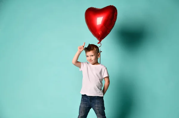 Menino amor segurar grande balão coração vermelho para celebrar dia dos namorados no verde popular — Fotografia de Stock