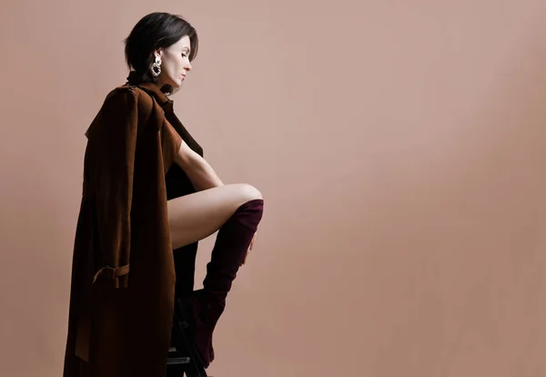 Seksi iç çamaşırı, kahverengi bahar ceket ve modern şık deri çizme genç güzel hippi kız oturma düşüncesinde — Stok fotoğraf
