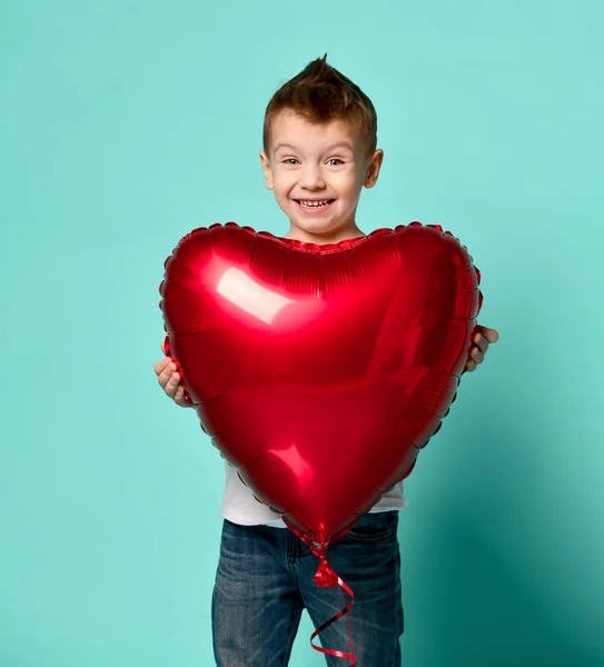 Menino amor segurar grande balão coração vermelho para celebrar dia dos namorados no verde popular — Fotografia de Stock