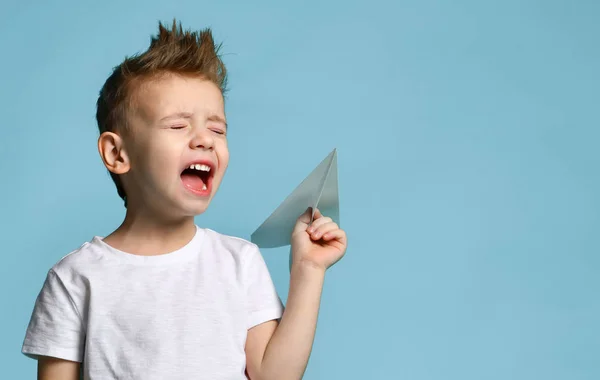 Jonge baby jongen jongen in wit t-shirt houden papier vliegtuig origami schreeuwen schreeuwen op blauw groene munt — Stockfoto