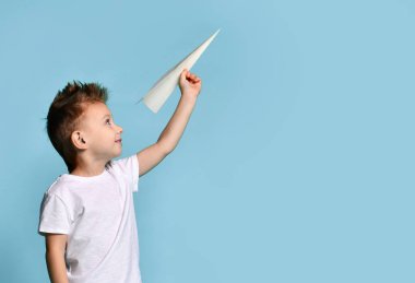 Genç bebek çocuk çocuk beyaz tişört içinde oyun kağıt uçak origami ile mutlu mavi yeşil nane gülümseyen tutun