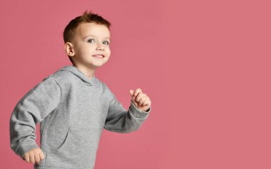 Mutlu pembe üzerinde gülümseyen çalışan serbest metin kopya alanı ile gri kapşonlu erkek çocuk genç bebek