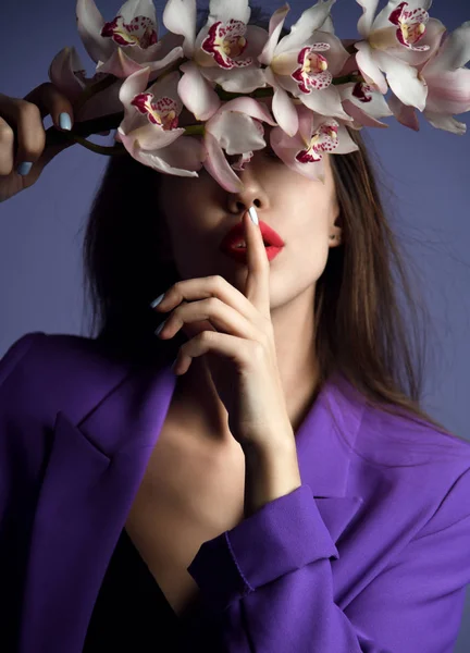 Mooi meisje met orchideebloemen. Schoonheid model vrouw gezicht op paarse achtergrond — Stockfoto