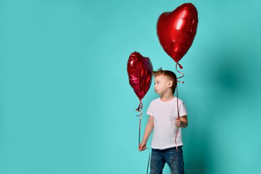 Küçük çocuk aşk başka bir kırmızı kalp balon popüler yeşil tarafından üzgün ve Sevgililer günü kutlamak için büyük kırmızı kalp balon tutun 