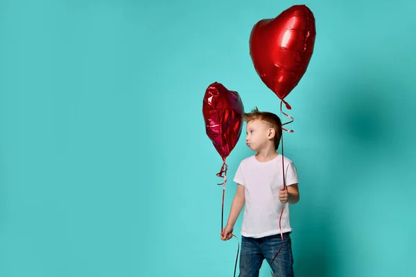 Küçük çocuk aşk başka bir kırmızı kalp balon popüler yeşil tarafından üzgün ve Sevgililer günü kutlamak için büyük kırmızı kalp balon tutun — Stok fotoğraf