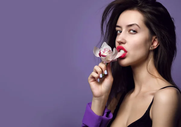 Hermosa chica con flores de orquídea. Belleza modelo mujer cara sobre fondo púrpura — Foto de Stock