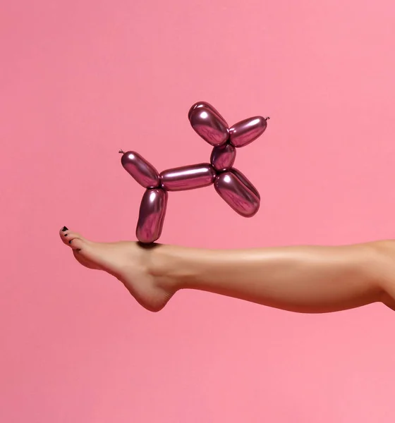 Женская нога и композиция из воздушных шаров на розовом фоне — стоковое фото