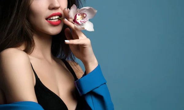 Hermosa chica con flores de orquídea. Belleza modelo mujer cara sobre fondo púrpura — Foto de Stock