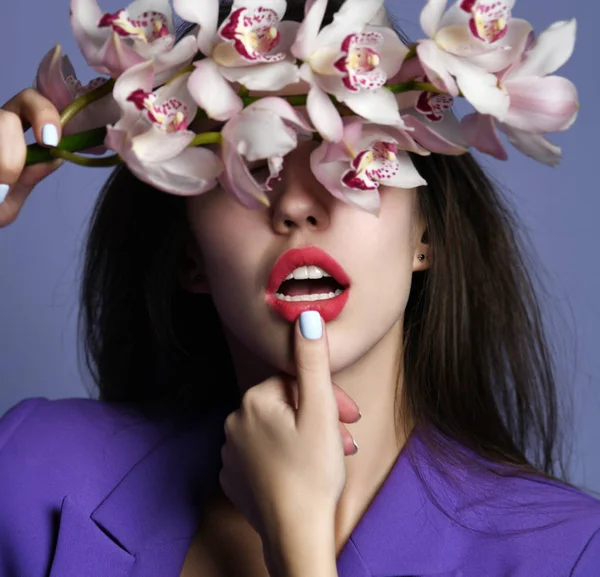 Beautiful girl with orchid flowers. Beauty model woman face on purple background — Stock Photo, Image