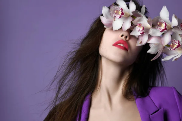 Beautiful girl with orchid flowers. Beauty model woman face on purple background — Stock Photo, Image