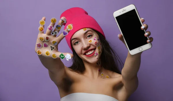 Mujer con populares social móvil emoji sonrisas pegatinas para el teléfono celular en sus manos feliz sonriendo mostrando pantalla de visualización en blanco —  Fotos de Stock