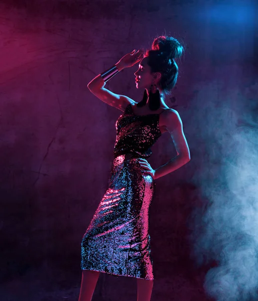 Seksi esmer kadın moda altın ışıltı elbiseyi koyu mavi ve pembe neon ışık poz güzel moda — Stok fotoğraf