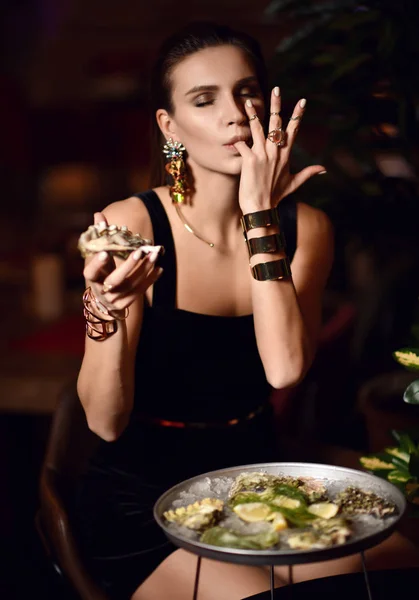 Schöne sexy Mode brünette Frau im teuren Restaurant essen Austern und lecken einen Finger — Stockfoto