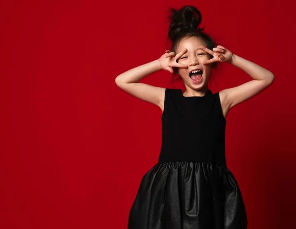 Schattig klein Aziatisch meisje ballerina in prachtige zwarte jurk is weergegeven: vredesteken dansen op rood — Stockfoto
