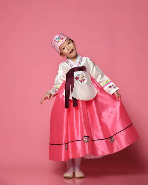 Bambina coreana in abito tradizionale di seta per festeggiare il nuovo anno danzando sul rosa — Foto Stock