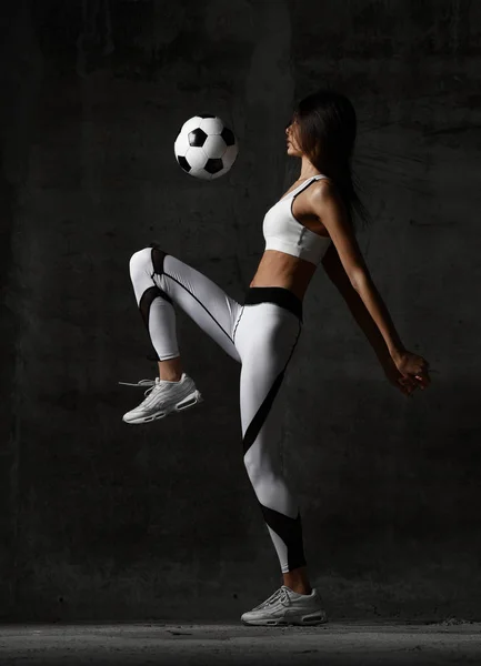 Soccer woman player jumps and hit the ball strike in the middle on concrete loft wall — Stock Photo, Image