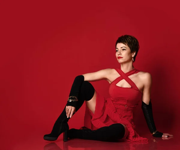 Portrait of a professional short hair business woman in red dress and long boots on red