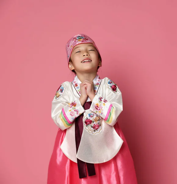 Bambina coreana in abito tradizionale di seta per la celebrazione del nuovo anno su rosa con le mani in segno di preghiera — Foto Stock