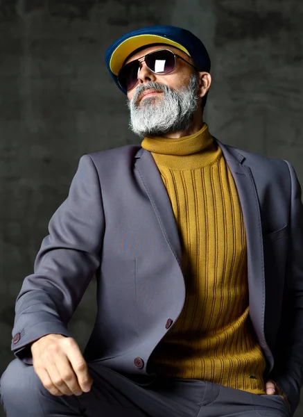 Brutal senior white bearded man in classic grey suit, green sweater, cap and aviator sunglasses stylish fashionable men — Stock Photo, Image