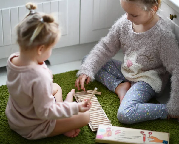 Deux gamines jouent à un jeu éducatif sur tapis vert dans leur chambre blanche — Photo