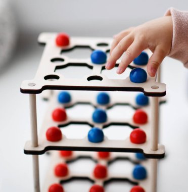 pembe gömlekli çocuk kız küçük kırmızı ve mavi topları ile eğitici bir oyun oynuyor