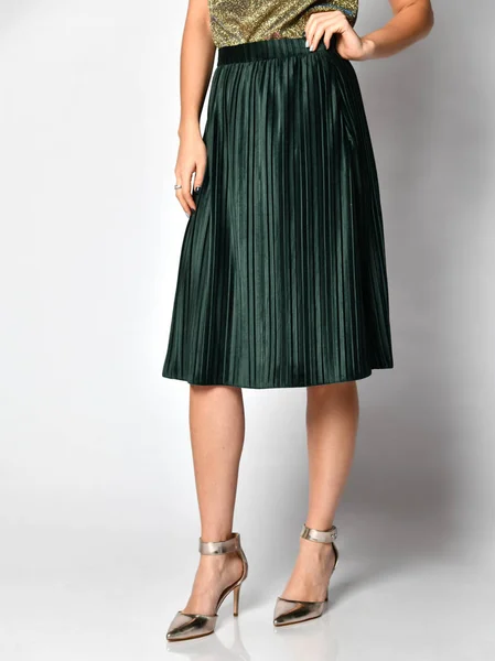 Woman legs in green skirt dress in silver medium hills shoes on gray