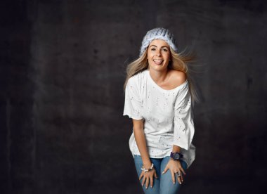 Hafif mavi örgü şapka ve kot mutlu gülümseyen göstermek dil tease kara günü sarışın kadın