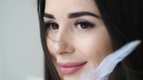 Portret van mooie vrouw spelen met veer sexy in de buurt van haar gezicht close-up — Stockvideo