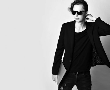 Dizüstü bilgisayarı olan genç modern bir adam dirseği resmin kenarında bedava metin alanının yanında duruyor.