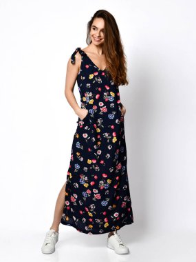 Genç, güzel bir kadın çiçek desenli bir elbiseyle, yüksek tepelerde, beyaz bir bedende poz veriyor.