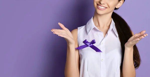 Woman with purple ribbon to world epilepsy day, cancer day poses like she holds something on open palms hands