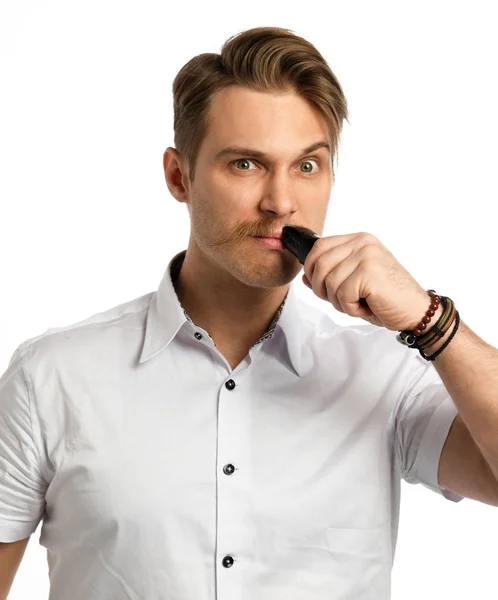 Handsome young bearded man trimming his beard with a trimmer isolated on a white — Stock Photo, Image