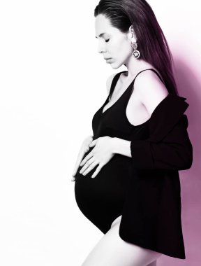 Gebelik, annelik, hazırlık ve beklenti kavramı. Güzel moda hamile kadın göbek ellerini tutar 