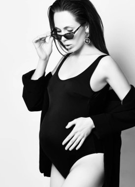 Gebelik, annelik, hazırlık ve beklenti kavramı. Güzel moda hamile kadın göbek ellerini tutar 