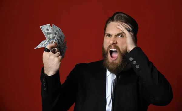 Ділова людина в чорному костюмі тримає американські долари сотні банкнот і голосно кричить Ах, мій Бог — стокове фото