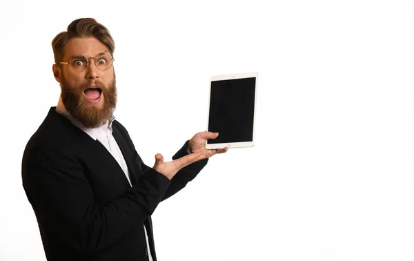 Hombre de negocios sorprendido en traje negro y camisa blanca sostienen la computadora de la tableta en gafas con mano de punta de barba —  Fotos de Stock