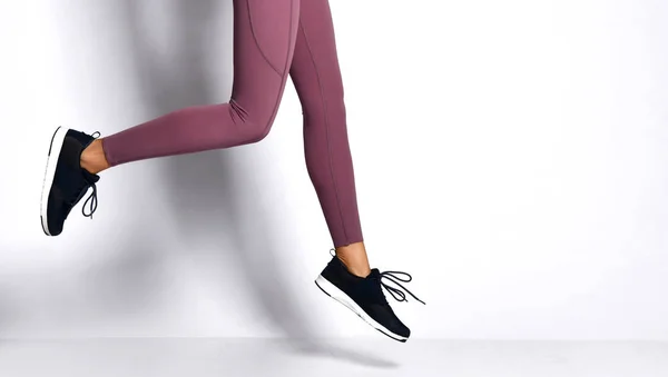 Closeup woman legs running jogging doing  workout exercise in sport wear pants on gray