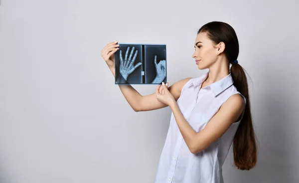 Brunette woman doctor or clinic patient holds hands X-ray good examination and looks at it satisfied — Stock Photo, Image