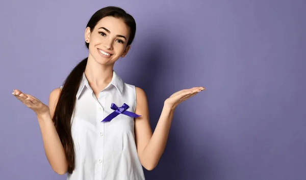 Slim woman with purple ribbon to world epilepsy day, cancer day poses like she holds something on open palms hands